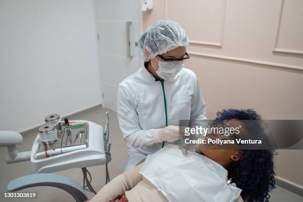 young woman smiling while having dental exam - eye protection stock pictures, royalty-free photos & images