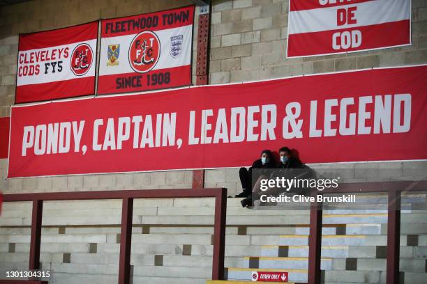 An empty stand as two match day staff watch during the Sky Bet League One match between Fleetwood Town and Doncaster Rovers at Highbury Stadium on...