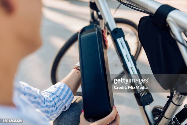 oigenkännlig kvinna byter batterier på sin elcykel - elcykel bildbanksfoton och bilder