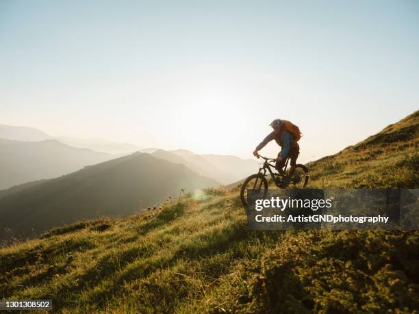 mountainbiker, der bei sonnenuntergang bergab fährt. - motorradfahrer stock-fotos und bilder