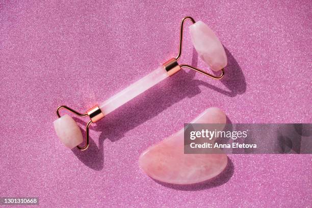 quartz pink roller and guasha for face massage with shade on glitter pink background. trendy procedures of the year. health and wellness concept - rolo para pintar paredes imagens e fotografias de stock