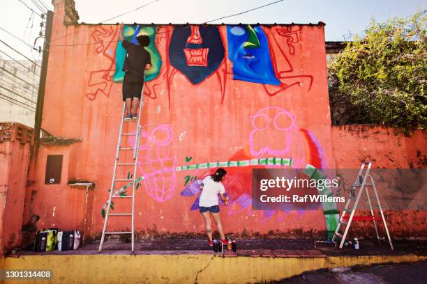 young man and woman creating graffiti on an outside wall. street art. - ribeirão preto stock pictures, royalty-free photos & images