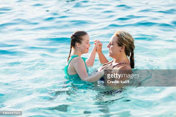 mother and girl with down syndrome swimming in pool - kid bath mother stock pictures, royalty-free photos & images