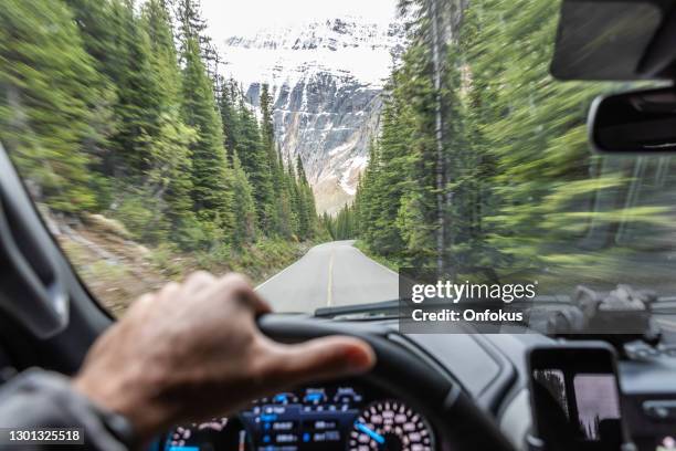 pov auto fährt auf empty road in den kanadischen rockies im sommer, kanada - blick durch kameraobjektiv stock-fotos und bilder