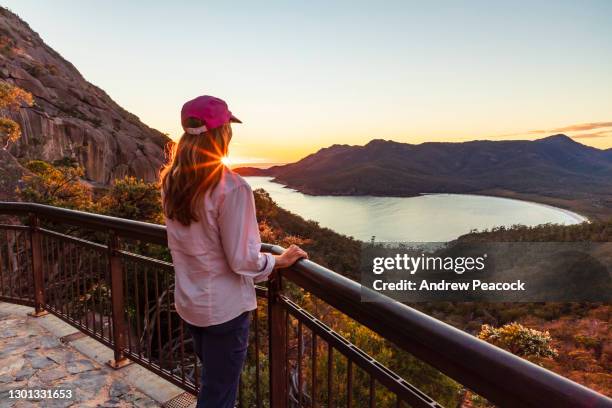 una mujer observa el amanecer en wineglass bay lookout, parque nacional freycinet - tasmania fotografías e imágenes de stock