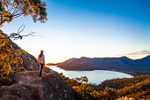A woman watches sunrise at Wineglass Bay lookout, Freycinet National Park
