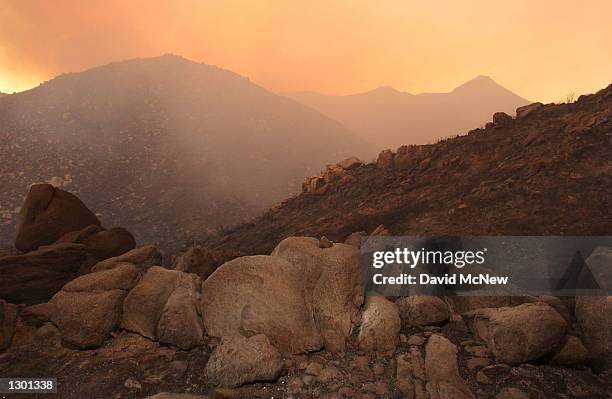 Charred rocks are left in a smokey landscape near the border of the Anza-Borrego Desert State Park where the out-of-control Pine Fire has grown to...