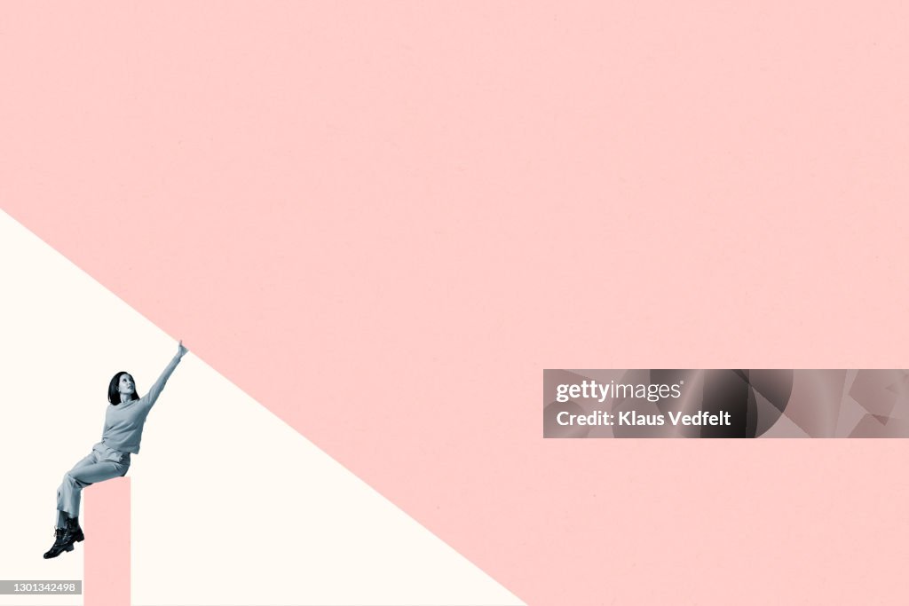 Young woman on column touching coral ceiling