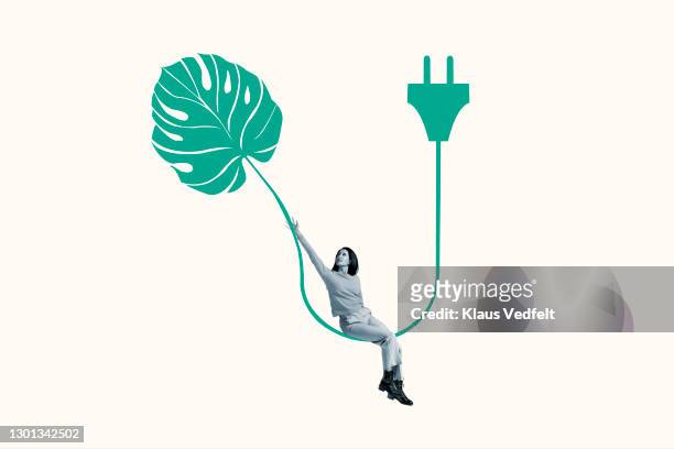 woman sitting on green cable with leaf and plug - electricity white background stock pictures, royalty-free photos & images