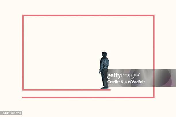 rear view of young man standing inside red box - constraints stock-fotos und bilder