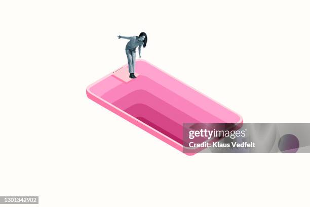 woman looking down deep hole in large pink smart phone - addiction photos et images de collection