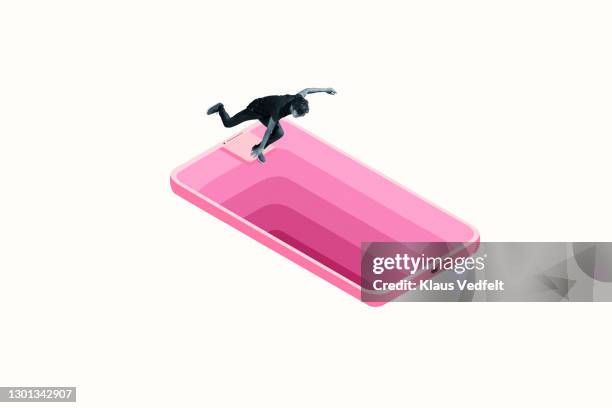 man falling down deep hole in large pink smart phone - eenheid stockfoto's en -beelden