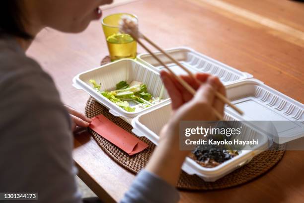 une femme mangeant une boîte à lunch à sortir à sa table à la maison. - plateau à compartiments photos et images de collection