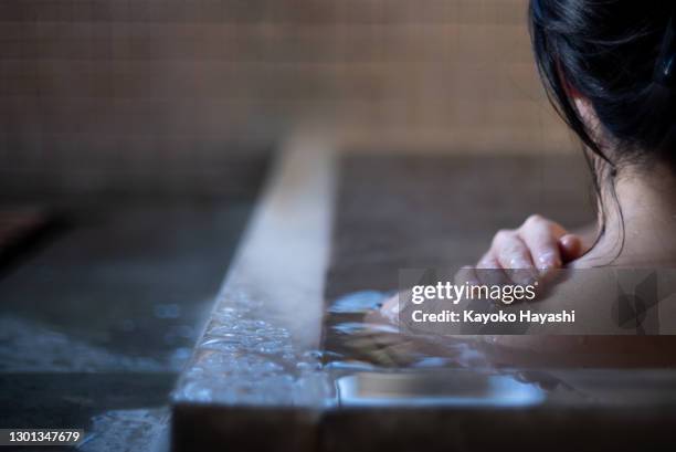 an asian woman takes a bath in a japanese hot spring. - hydrotherapy stock pictures, royalty-free photos & images