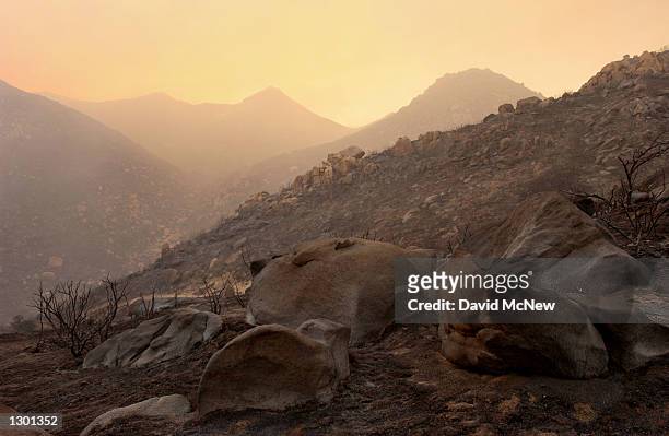 Charred rocks are left in a smokey landscape near the border of the Anza-Borrego Desert State Park where the out-of-control Pine Fire has grown to...