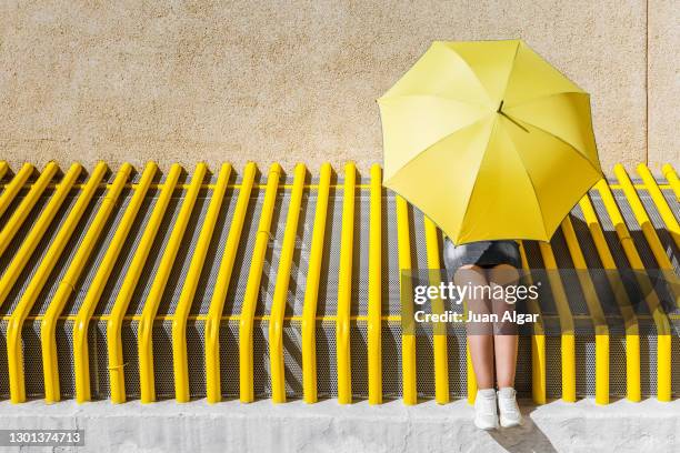 woman with umbrella resting near wall in sunny day - shy bildbanksfoton och bilder