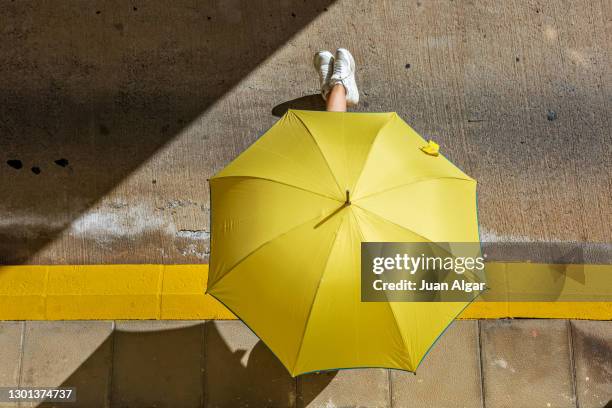 woman resting under umbrella on sunny street - older woman legs - fotografias e filmes do acervo