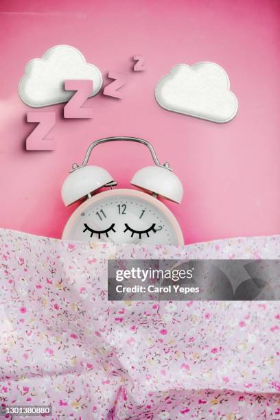 pink alarm clock  sleeping in bed - daylight saving time foto e immagini stock