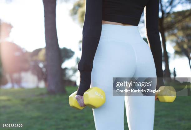 midsection of woman working out in the park, using weights - leggings foto e immagini stock