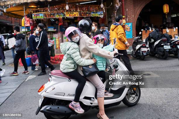 Two children ride on a scooter with their mother on February 10, 2021 as people prepare for Chinese New Year at Dihua Street in Taipei, Taiwan....