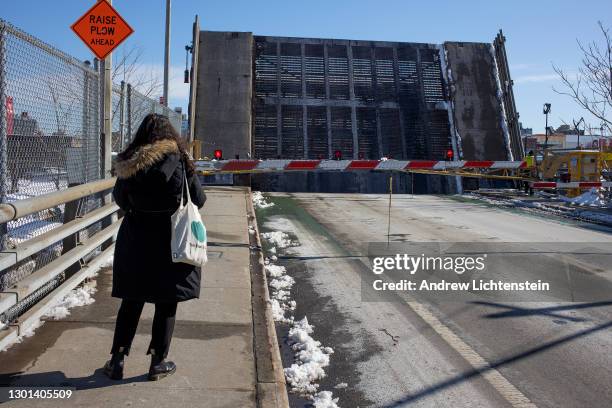 Pedestrian waits for a drawbridge raised to allow a passing boat to travel through the Gowanus Canal to come down, February 10, 2021 in the Gowanus...