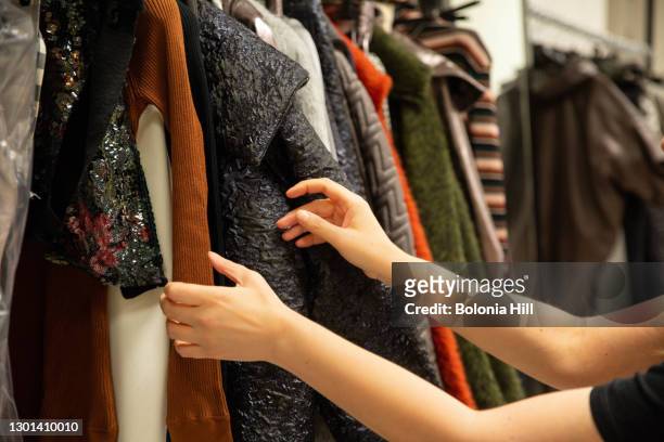 manos de mujer buscando entre prendas colgadas en un burro - placard fotografías e imágenes de stock