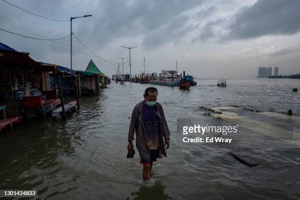 An Indonesian man walks along a ferry terminal on the North coast of Jakarta which is flooded every morning during high tide on February 09, 2021 in...