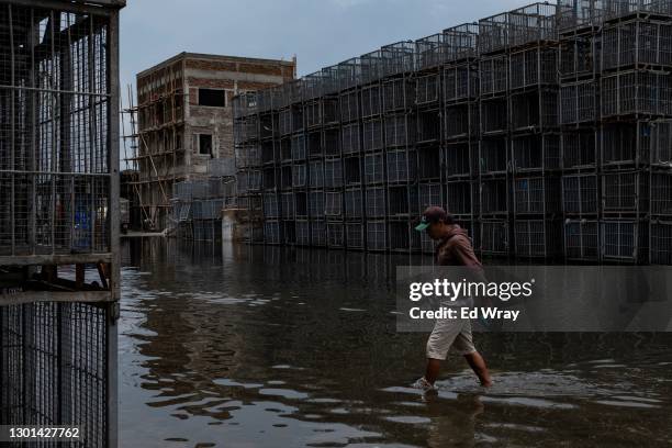 A man walks through fishing port flooded by the high tide due to the sinking of coastal land on February 10, 2021 in Jakarta, Indonesia. Jakarta,...