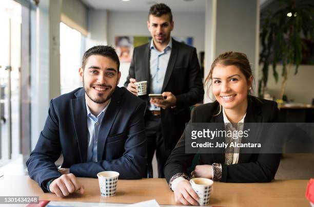office workers taking a break drinking coffee and smiling looking at camera - bank office clerks stock pictures, royalty-free photos & images