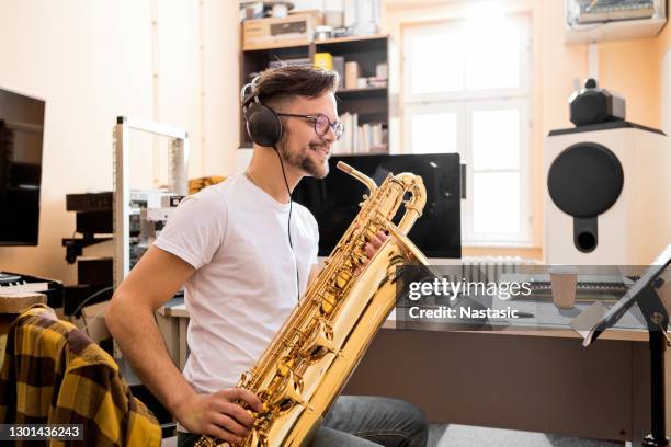 young man playing saxophone smiling - saxophonist stock pictures, royalty-free photos & images