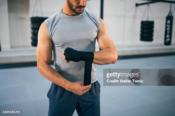 pugile maschio che fascia le mani con un involucro per le mani da combattimento per la sessione di allenamento kickboxing - fighting ring foto e immagini stock