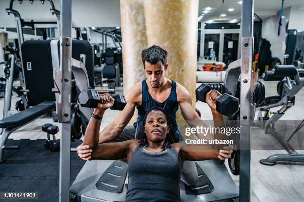 trainer helping woman exercising in gym - personal trainer stock pictures, royalty-free photos & images