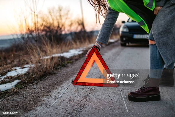 mujer colocando triángulo de emergencia - triángulo-de-advertencia fotografías e imágenes de stock