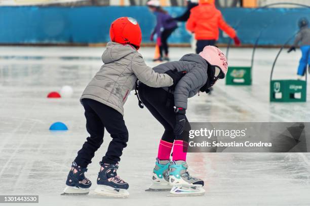 child's first lessons of skating on the rink, in the winter in the city on the street. girls girlfriends. - figure skating child stock pictures, royalty-free photos & images