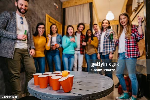 young people playing beer pong in hostel - beer pong stock pictures, royalty-free photos & images