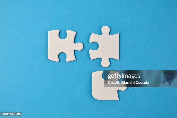 white puzzle pieces on blue background - pièce de puzzle photos et images de collection