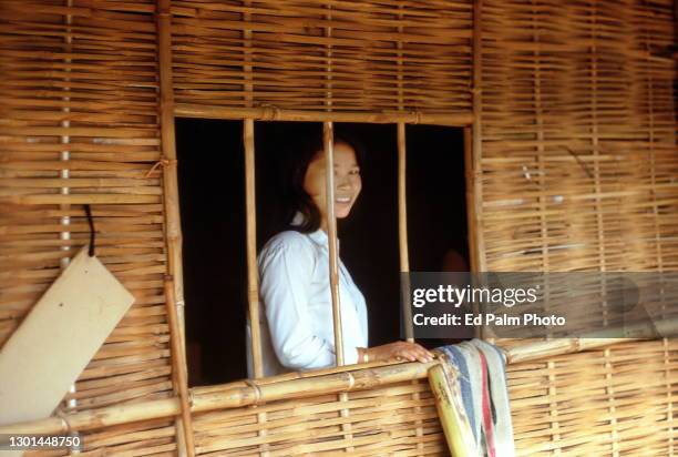 Shy young woman peeking out from behind the bamboo wall of her house in Cam Hieu, Quang Tri Province, Vietnam, on September 21, 1967.