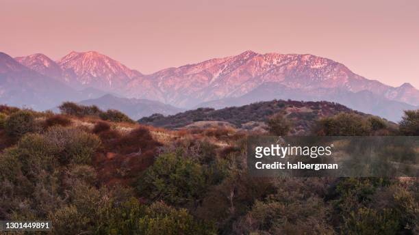 cyclist riding on trail with snowy mountains in distance - aerial - san gabriel mountains stock pictures, royalty-free photos & images