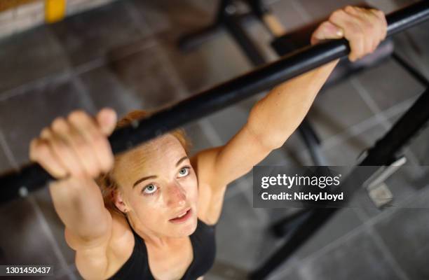 geschikte jonge vrouw die kin-ups tijdens een training bij de gymnastiek doet - chin ups stockfoto's en -beelden