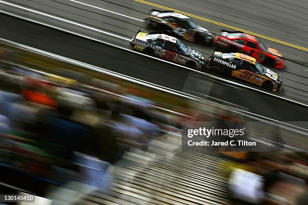 Jeff Burton, driver of the Caterpillar Chevrolet, and Clint Bowyer, driver of the Chevy 100 Years Chevrolet, race Jamie McMurray, driver of the Bass...