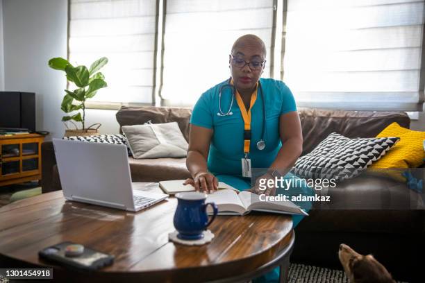 zwarte vrouwelijke verpleegster die tussen verschuivingen bestudeert - student reading book stockfoto's en -beelden
