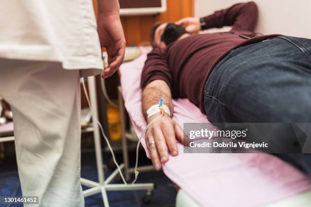 medical staff taking care of a patient with perfusion drip - receiving blood stock pictures, royalty-free photos & images