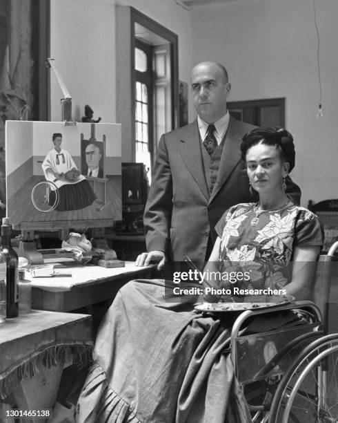 Mexican artist Frida Kahlo poses with Dr Juan Farill, beside a painting that also depicts the pair, Mexico City, Mexico, 1952.