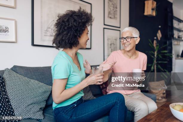 senior woman enjoying talking with her young neighbor - neighbor stock pictures, royalty-free photos & images