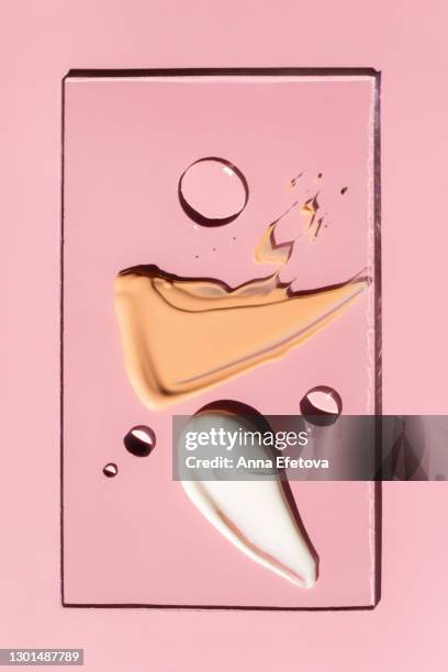 drops and smears of various cosmetic products on pink background. trendy selfcare products of the year - make up grundierung stock-fotos und bilder