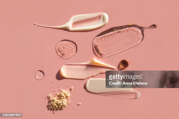 drops and smears of various cosmetic products on pink background. trendy selfcare products of the year - couleur crème photos et images de collection