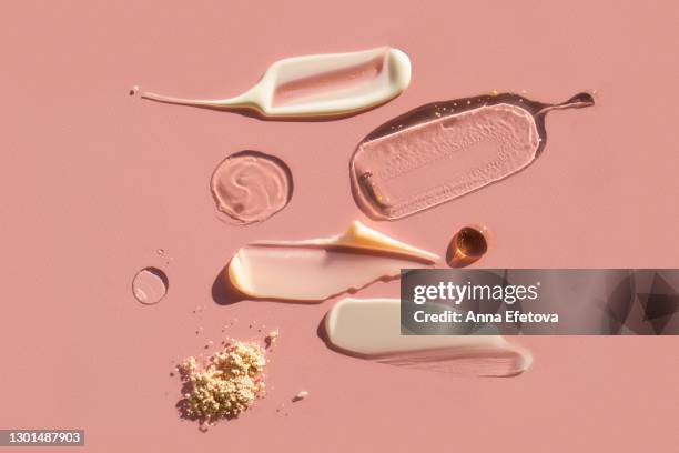 drops and smears of various cosmetic products on pink background. trendy selfcare products of the year - skin texture stockfoto's en -beelden