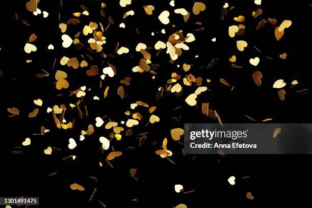 golden hearts confetti splashing over black background. valentine's day concept - falling in love stockfoto's en -beelden