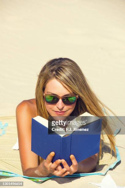 young woman reading a book on the beach - j lee fotografías e imágenes de stock