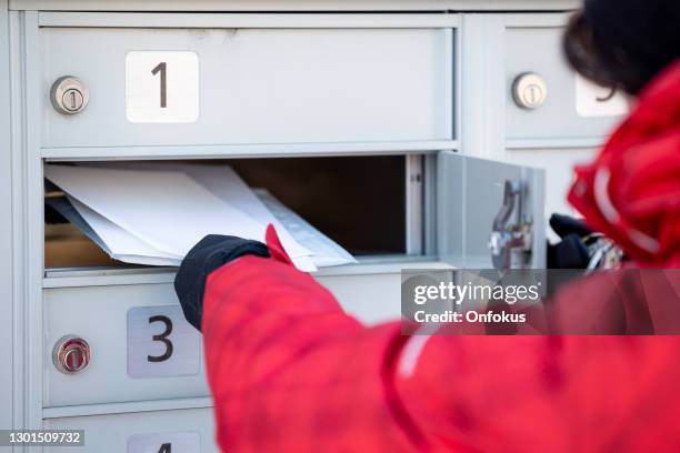 woman wearing gloves picking up the mail at postal mailbox during winter season - message box stock pictures, royalty-free photos & images